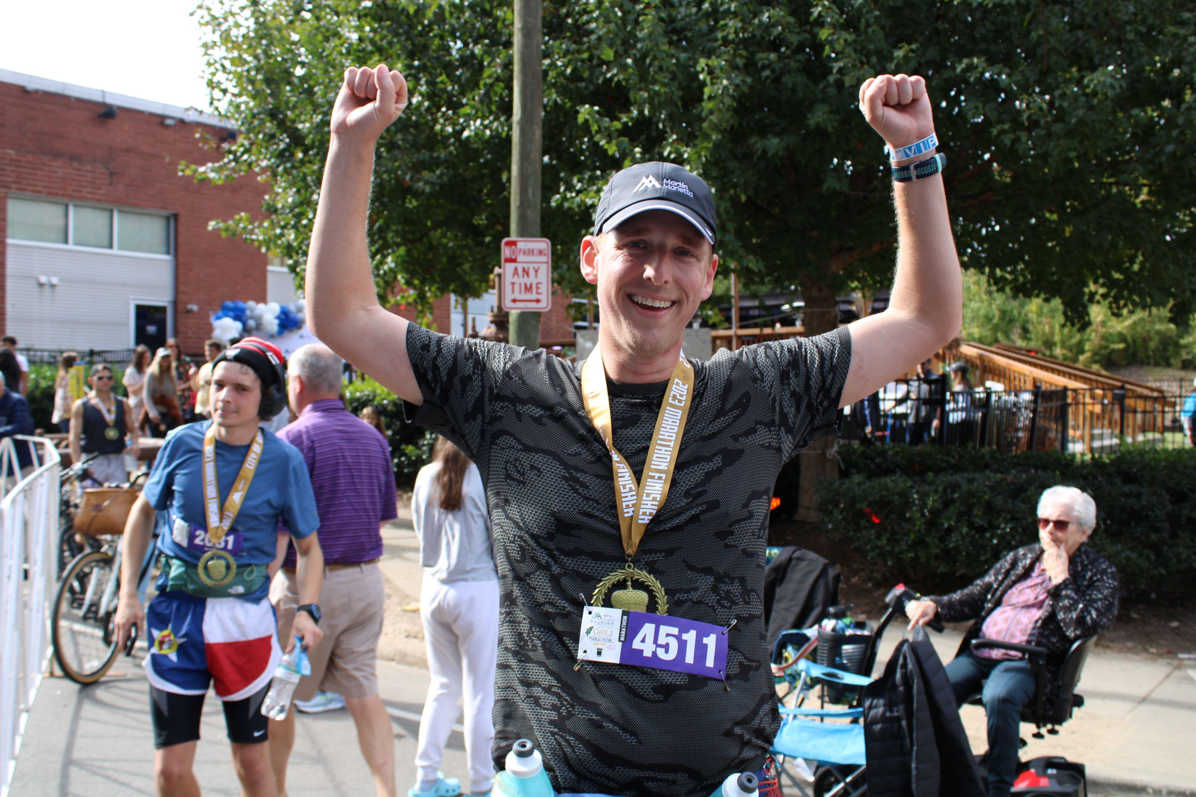 Curtis Smith throws his hands up in victory after crossing the finish line at the Martin Marietta City of Oaks Marathon.