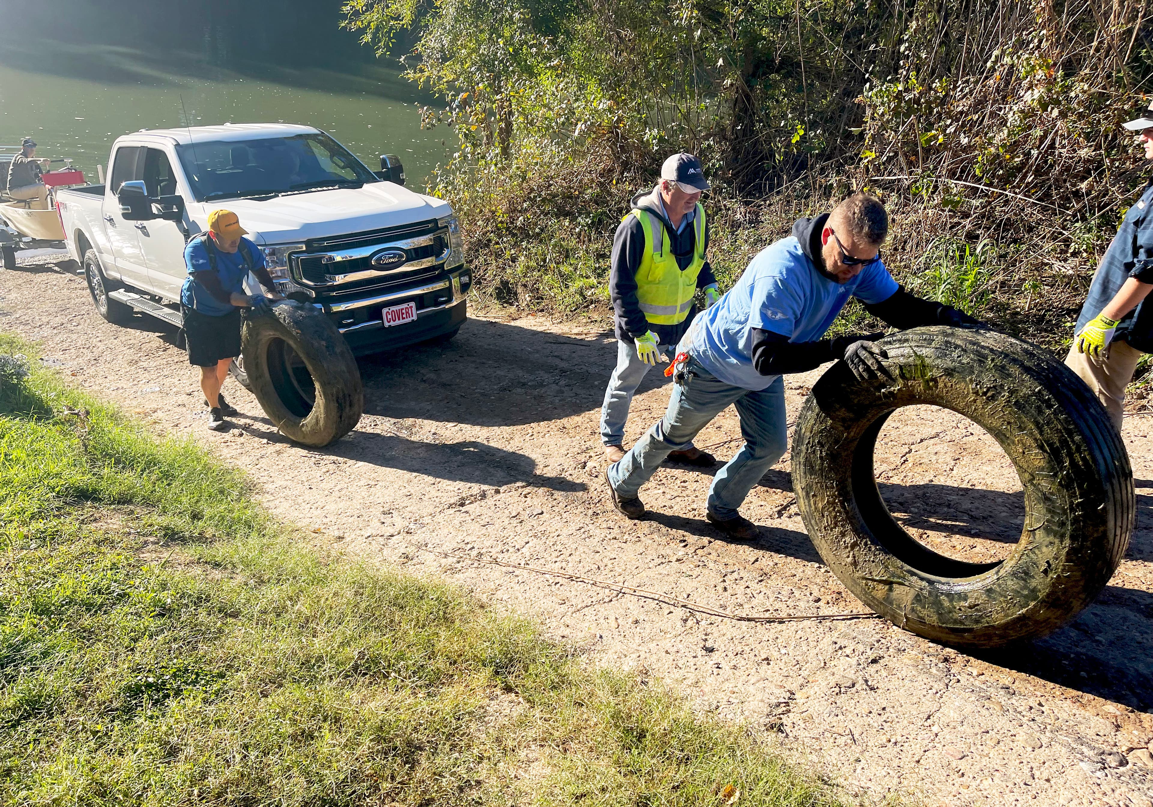 Senior Sales Representative Chris Keathley (front) and Alex Young – husband of Jayde Young – (rear) remove a pair of tires from the Colorado River during the LoCo Trash Bash.