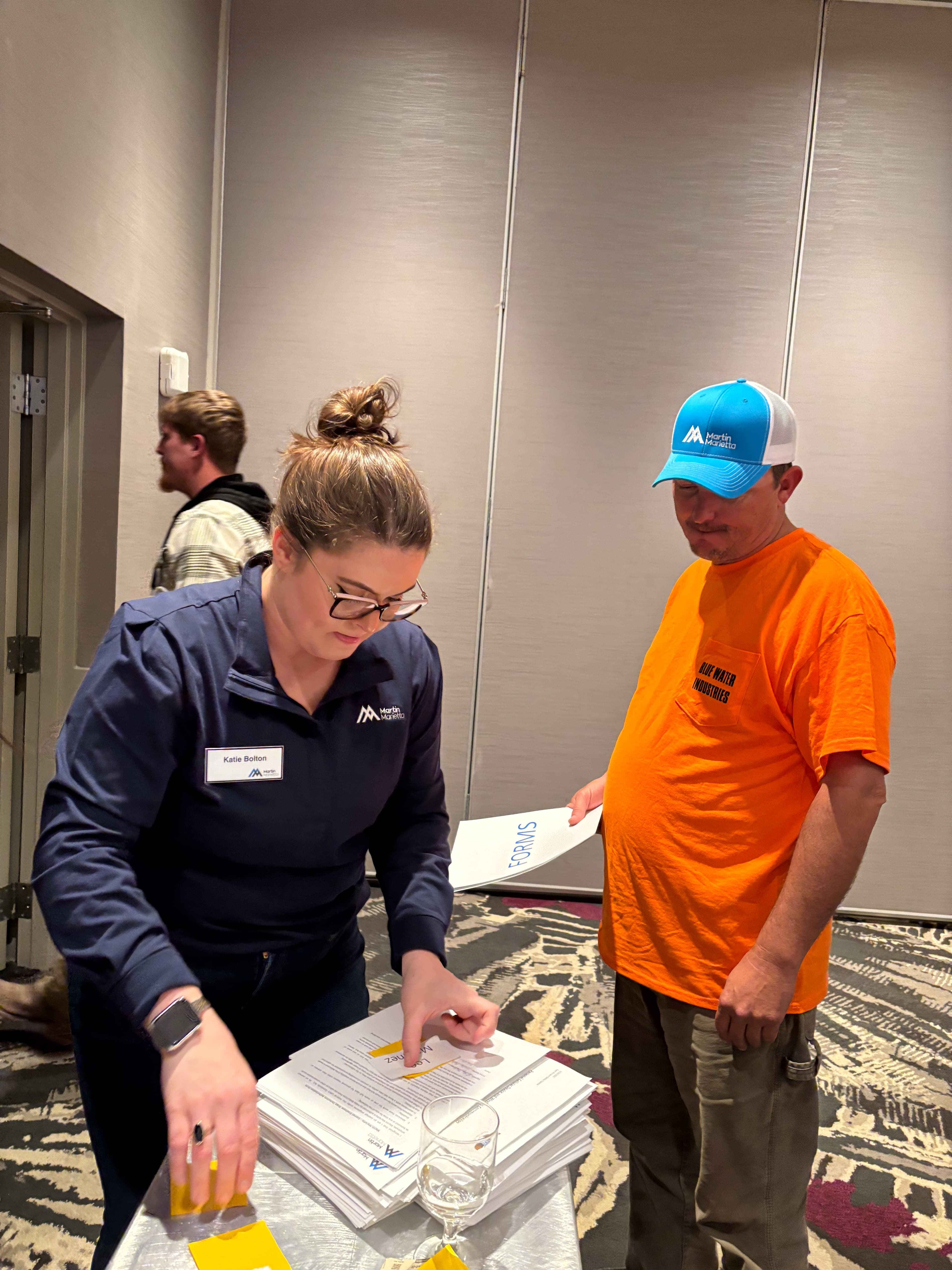 Katie Bolton, an East Division talent acquisition senior specialist, hands out HR forms to new ONE team members at the Huntsville, Alabama, onboarding event.