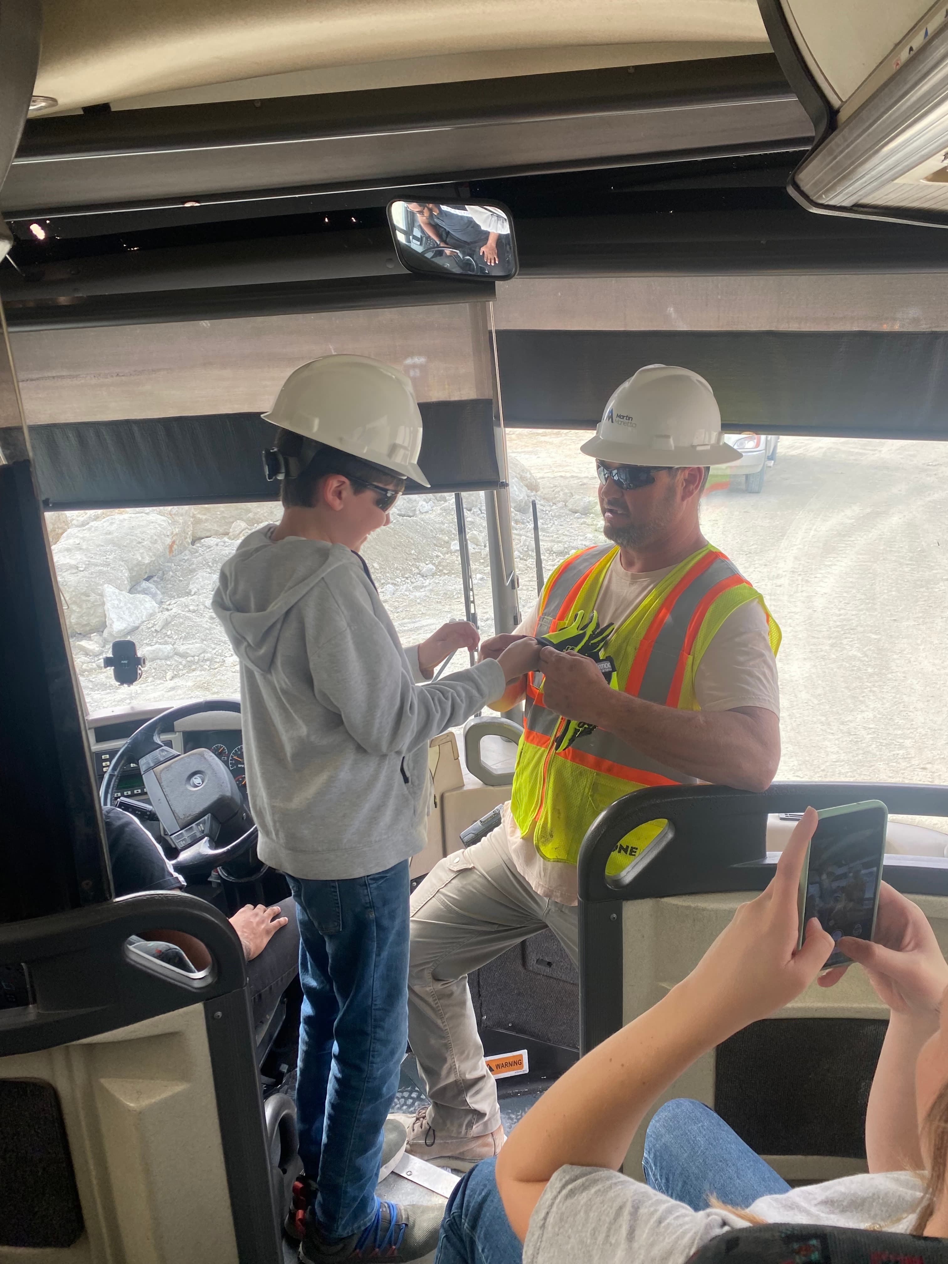 Grayson Osborne, a sixth-grade student battling brain cancer, put on safety equipment while preparing to ride in a haul truck at Berkeley Quarry.